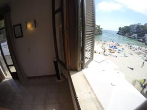 a room with a view of a beach with people at Hostal Playa in Cala Santanyi