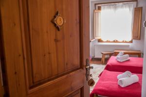 a bedroom with two beds with red sheets and white towels at Ξενώνας Πατρικό in Neraidochori