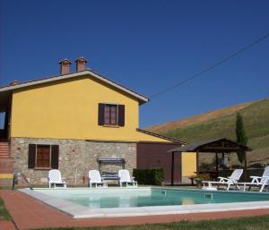 a pool in front of a house with white chairs at Agriturismo Podere Bellosguardo in Villamagna