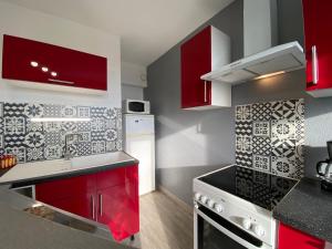 een keuken met rode kasten en zwarte aanrechtbladen bij PANORAMA Balcony in Pontorson