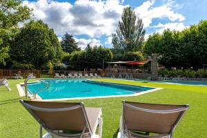 a swimming pool with two chairs in a yard at Camping maeva Escapades Millau Plage in Millau