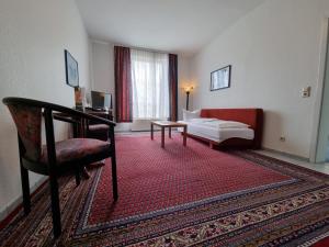 Zimmer mit einem Bett, einem Stuhl und einem Sofa in der Unterkunft Erbenholz Hotel in Hannover