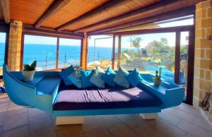 VILLE GIRASOLI "VILLA NELLA BAIA" with PRIVATE SWIMMING POOL في تريكاس: أريكة زرقاء في غرفة مطلة على المحيط