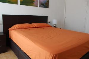 ロスピタレート・デ・リンファントにあるApartamento en primera línea de marのベッドルームにオレンジの掛け布団付きのベッド1台