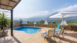 a swimming pool with two chairs and an umbrella at Finca Al-Zaytún Órgiva by Ruralidays in Órgiva