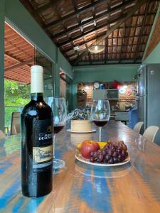 een fles wijn en een fruitschaal op een tafel bij Casa com os pés no mar em Iriri ES in Anchieta
