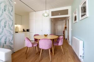 a kitchen and dining room with a table and pink chairs at Santa Luzia Views - Modern City Centre Apartment with Iconic Views in Viana do Castelo