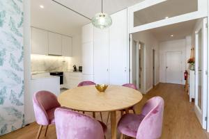a kitchen and dining room with a wooden table and pink chairs at Santa Luzia Views - Modern City Centre Apartment with Iconic Views in Viana do Castelo