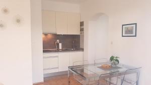eine Küche mit weißen Schränken und einem Glastisch in der Unterkunft Apartmani Milin in Zadar