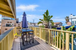 uma varanda com um guarda-sol, uma mesa e cadeiras em Mimi's and Nana's Beach House em San Diego