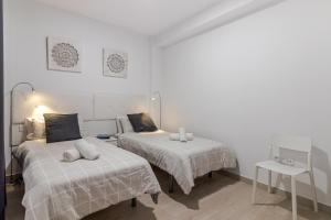 two beds in a room with white walls at Cozy Family Beach House in Las Palmas de Gran Canaria