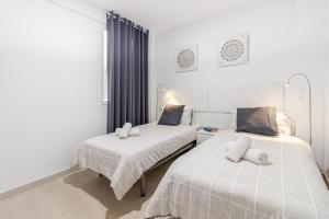 two beds in a room with white walls at Cozy Family Beach House in Las Palmas de Gran Canaria