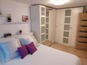 1 dormitorio con cama blanca y almohadas moradas en Marijampolės jaukūs apartamentai en Marijampolė