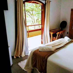 ヴィスコンデ・デ・マウアーにあるPousada Sitio do Viscondeのベッドルーム1室(ベッド1台付)、窓、バルコニーが備わります。
