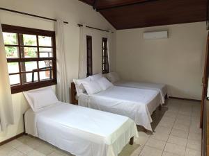 a bedroom with two beds and a window at Pousada Coração de Búzios in Búzios