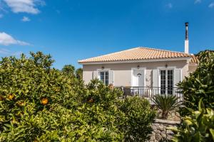 Kanelos Garden House في Dhrákas: بيت ابيض وامامه اشجار