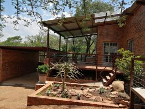 un patio con una terraza con un banco. en Bushbaby Cottage in Hartbeespoort, en Pretoria