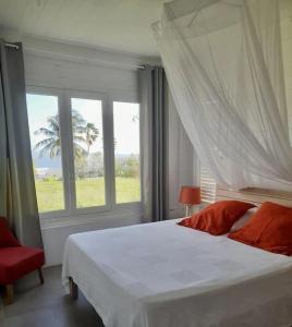 a bedroom with a white bed and a window at VILLA AQUA in Case-Pilote