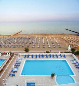 eine Aussicht über den Pool, die Stühle und das Meer in der Unterkunft Hotel Condor in Lido di Jesolo