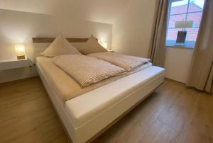 ein Bett mit zwei Kissen darauf in einem Zimmer mit Fenster in der Unterkunft Lüttje Friesenhuus in Greetsiel