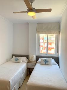 2 Betten in einem Schlafzimmer mit Deckenventilator in der Unterkunft Anacasa Puerta del Palmar AP2207 in Denia