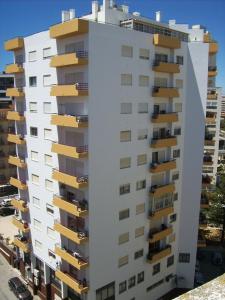 un edificio alto de color blanco con balcones amarillos en Apartamentos Turísticos Pérola da Rocha II, en Portimão