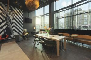a dining room with a table and chairs and windows at ibis Styles Arnhem Centre in Arnhem