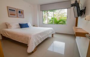 a white bedroom with a bed and a window at Magico Apartamento Frente al Mar 2 Habitaciones B11A in Coveñas