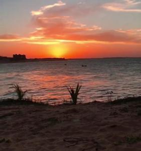 einen Sonnenuntergang am Strand mit Sonnenuntergang über dem Wasser in der Unterkunft EDEN Pousada in Lagoinha