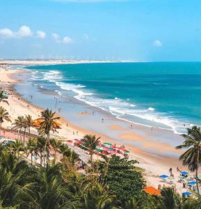 a beach with people and umbrellas and the ocean at EDEN Pousada in Lagoinha