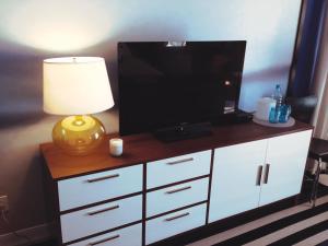 a tv on top of a white cabinet with a lamp at Montauk Blue Hotel in Montauk