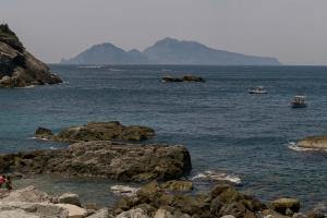 a body of water with rocks and boats in it at Maya Beach Resort in Massa Lubrense