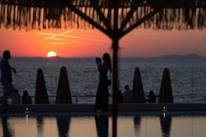 a woman taking a picture of the sunset at a resort at Maya Beach Resort in Massa Lubrense