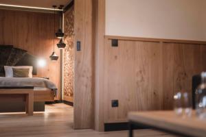 Habitación de hotel con cama y paredes de madera en Majestic Hotel & Spa Resort en Brunico