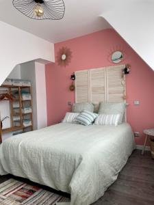 a bedroom with a large bed with pink walls at Du gite dans les Toiles in Wimereux