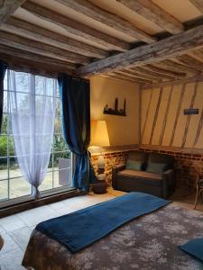 a bedroom with a bed and a couch and a window at L'escapade in Foulbec