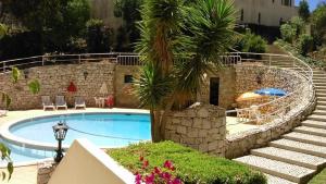 a swimming pool with a stone wall and a palm tree at Apartamentos Turísticos Pérola da Rocha II in Portimão