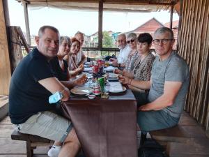 un grupo de personas sentadas en una mesa comiendo en ST 63 Home Stay & Tour Kampong Khleang, en Kâmpóng Khleăng