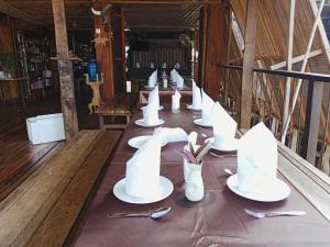 una mesa larga con platos blancos, tenedores y cucharas en ST 63 Home Stay & Tour Kampong Khleang, en Kâmpóng Khleăng