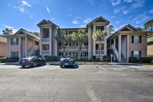 two cars parked in a parking lot in front of a building at Welcome to After Dune Delight Golf Course Condo! in Pawleys Island