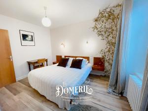 1 dormitorio con 1 cama con sábanas blancas y almohadas marrones en La Domerie - Maison d'hôtes en Aubrac