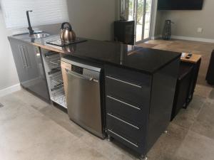 a kitchen with a black counter top and a dishwasher at SiriMiri Cottage Dullstroom in Dullstroom