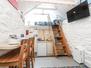 a kitchen with a table and a staircase in a room at The Old Stable in Helston