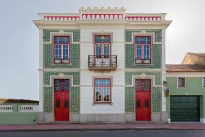 uma casa com portas vermelhas e uma varanda em Vintage Balcony Guesthouse em Ovar