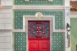 uma porta vermelha num edifício com uma parede verde e branca em Vintage Balcony Guesthouse em Ovar