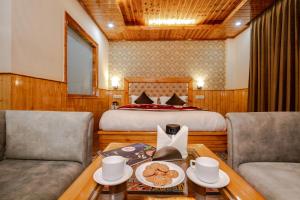 a bedroom with a bed and two chairs and a table at Hotel Hukam's Holiday Home in Kasol