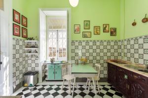 a kitchen with green walls and a table and chairs at Vintage Balcony Guesthouse & Suites in Ovar