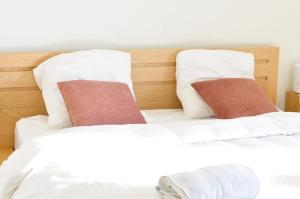 2 camas con sábanas blancas y almohadas rojas en APPART 2P AVEC PARKING ET BALCON - gare val d'europe 5mn - disney 10mn, en Montévrain
