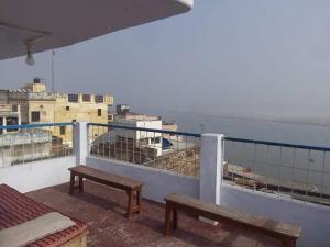 two benches sitting on a balcony overlooking the ocean at OM REST HOUSE in Varanasi
