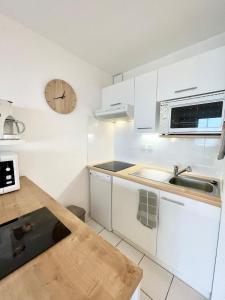 a kitchen with white cabinets and a clock on the wall at SPLENDIDE ! T2 Archi Cocooning Vue mer 180 in Ploemeur